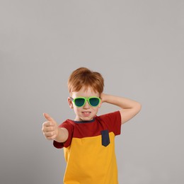 Cute little boy with sunglasses on light grey background