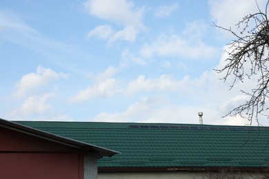 Photo of House with green roof under cloudy sky outdoors