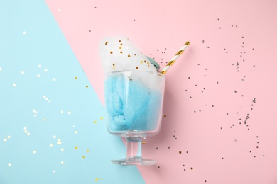 Glass with cotton candy and macaroon on color background, top view