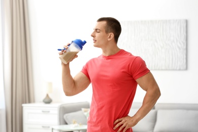 Athletic young man drinking protein shake at home