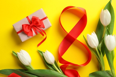 8 March card design with tulips and gift on yellow background, flat lay. International Women's Day