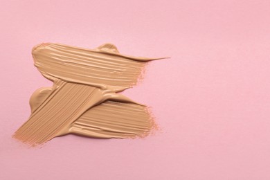 Sample of liquid skin foundation on pink background, top view. Space for text