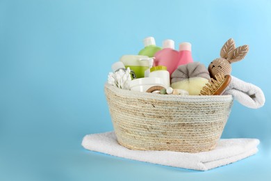 Basket with baby cosmetic products and accessories on light blue background. Space for text