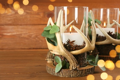 Stylish holders with burning candles, coffee beans and eucalyptus on wooden table. Space for text