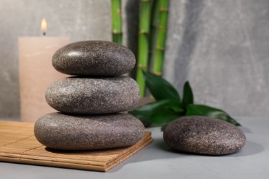 Spa stones, bamboo and candle on light grey table, space for text