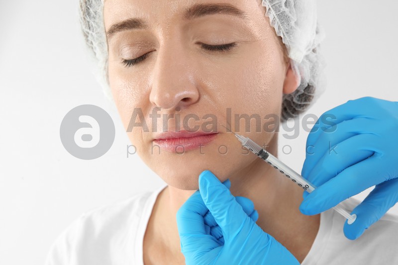 Mature woman getting facial injection on white background. Cosmetic surgery concept
