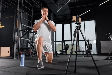 Photo of Trainer streaming online workout with phone at gym