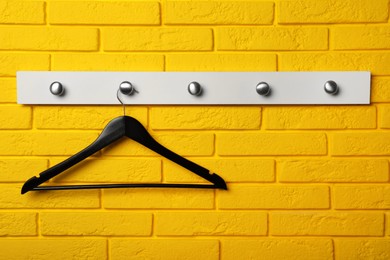 Photo of Rack with empty clothes hanger on yellow brick wall