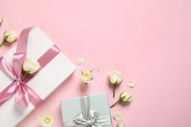 Elegant gift boxes and beautiful flowers on pink background, flat lay. Space for text