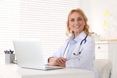 Photo of Doctor with laptop and stethoscope at workplace in clinic. Online medicine concept