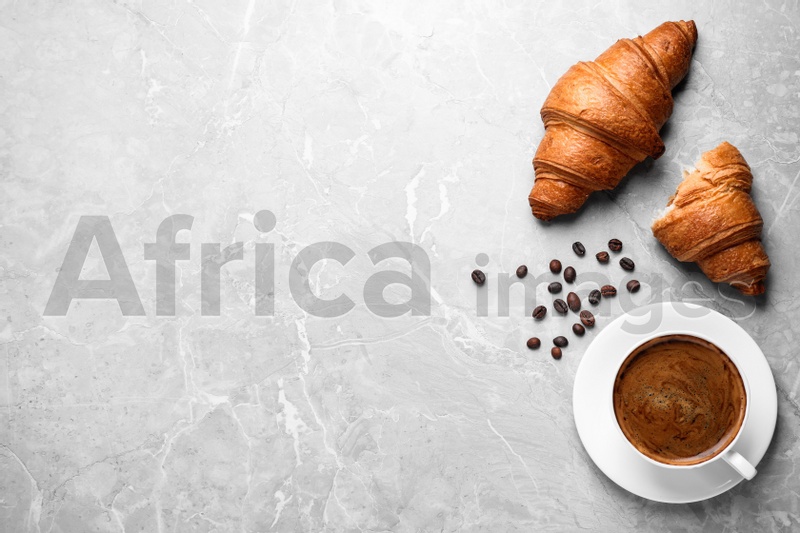 Tasty fresh croissants and coffee on light grey marble table, flat lay. Space for text