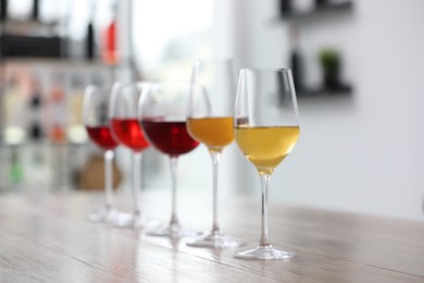 Different sorts of wine in glasses prepared for tasting on wooden table indoors