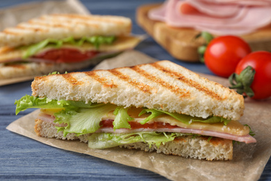 Tasty sandwich with ham on blue wooden table, closeup