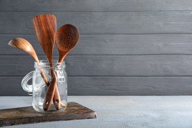 Set of kitchen utensils in holder on grey wooden table, space for text