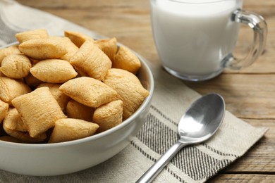 Bowl of sweet crispy corn pads and milk on wooden table, closeup. Breakfast cereal