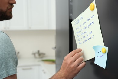 Man checking to do list on fridge in kitchen, closeup