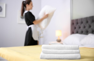 Stack of towels and blurred maid on background in hotel room