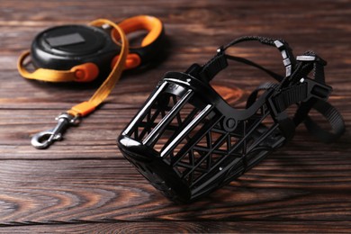 Photo of Black plastic dog muzzle and leash on wooden table