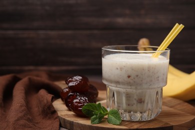 Photo of Glass of delicious date smoothie, mint and dried fruits on wooden board. Space for text