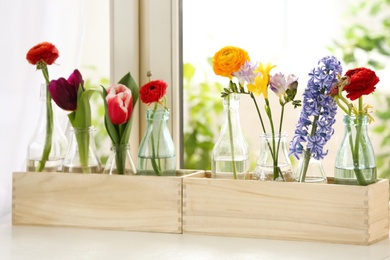 Photo of Beautiful spring flowers in wooden crates on window sill