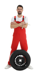 Full length portrait of professional auto mechanic with wheel and lug wrench on white background