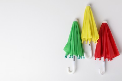 Small color umbrellas on white background, top view. Space for text