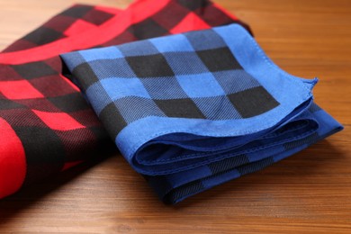 Folded red and blue checkered bandanas on wooden table, closeup