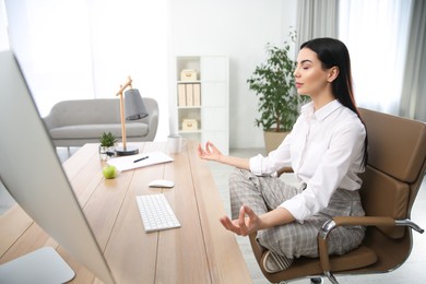 Young woman meditating at workplace. Stress relief exercise