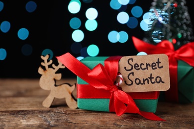 Present from secret Santa on wooden table against blurred lights