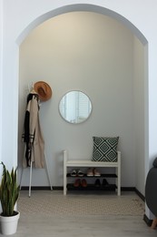 Hallway interior with clothes rack and round mirror