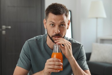 Man drinking delicious juice from bottle at home