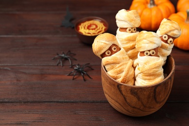 Spooky sausage mummies for Halloween party served on wooden table, space for text