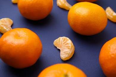 Photo of Fresh juicy tangerines and segments on blue table