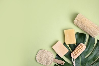 Eco friendly personal care products and leaf on light green background, flat lay. Space for text