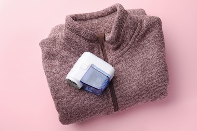 Photo of Fabric shaver and sweater on pink background, top view
