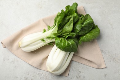 Fresh green pak choy cabbages with water drops on light grey table, flat lay