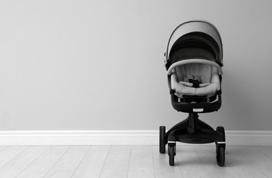 Baby carriage. Modern pram near light grey wall, space for text