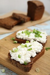 Photo of Bread with cottage cheese and green onion on table, closeup