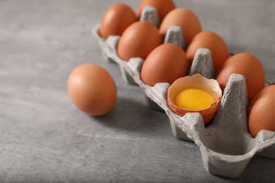 Photo of Fresh raw chicken eggs in carton on grey table, closeup