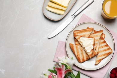 Tasty toasts served with spreading butter and honey on light grey marble table, flat lay. Space for text