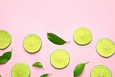 Juicy fresh lime slices and green leaves on pink background, flat lay. Space for text
