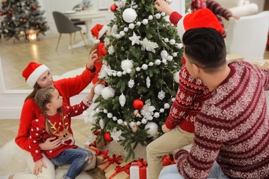 Happy family with cute children decorating Christmas tree together at home