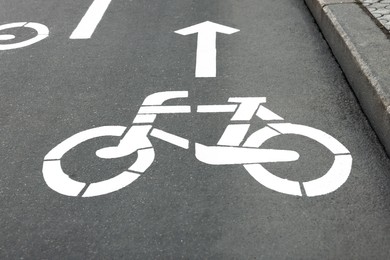 Bicycle lane with sign and arrow pointing direction on asphalt, closeup