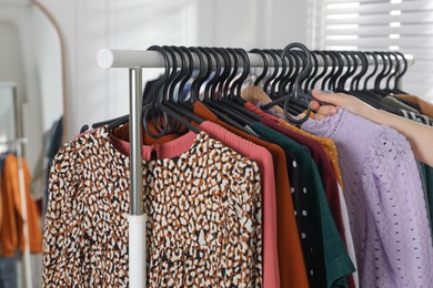 Photo of Woman picking clothes from rack indoors, closeup. Fast fashion