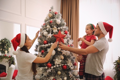 Family decorating Christmas tree with star topper indoors