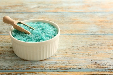 Photo of Bowl and scoop with turquoise sea salt on rustic table, space for text