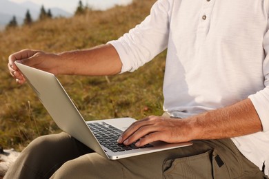Man working with laptop outdoors on sunny day, closeup