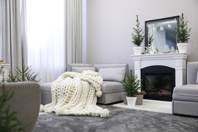 Stylish living room interior with little fir trees and Christmas decorations