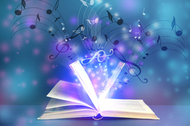 Symphony shining with musical notes from open book on color background 