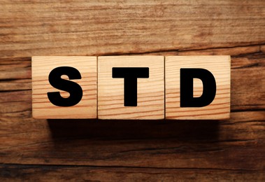 Photo of Wooden cubes with letters STD (sexually transmitted diseases) on table, flat lay